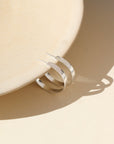 A medium thick hammered sterling silver hoop displayed on a cream display. 