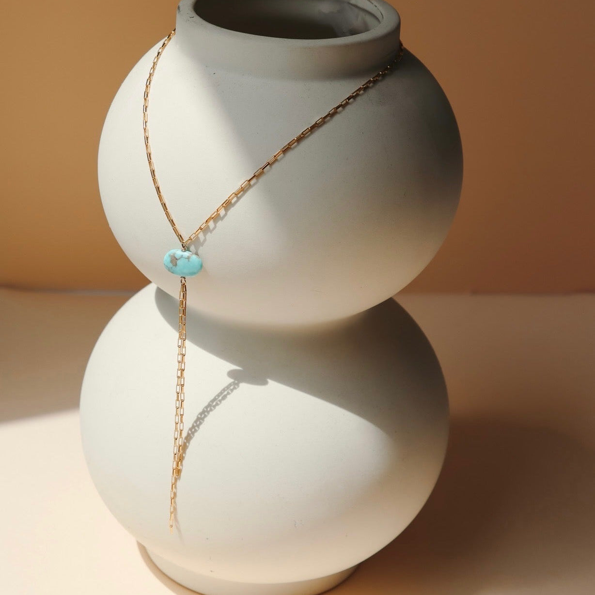 14k gold fill chain lariat necklace with oval turquoise stone on a light vase