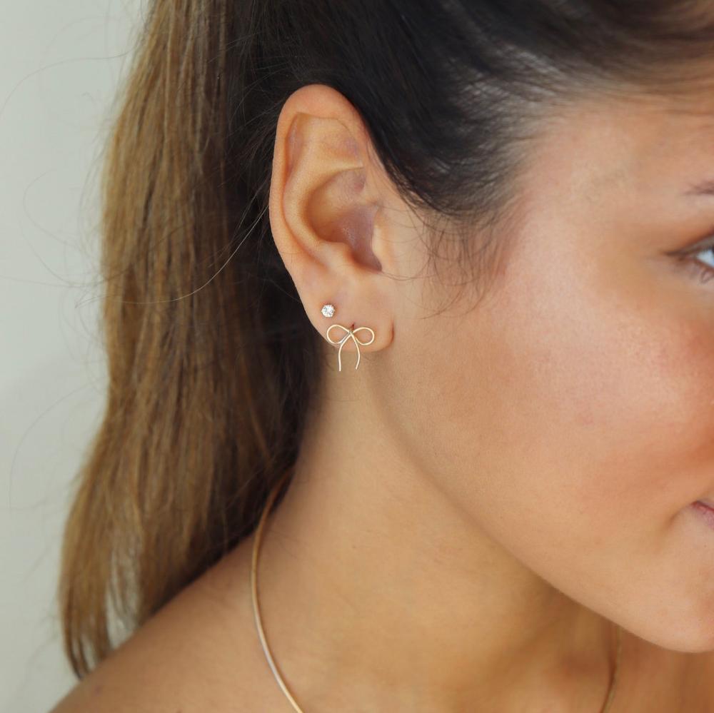 model wearing 14k gold fill hand shaped bow stud earrings with gemstone stud earrings