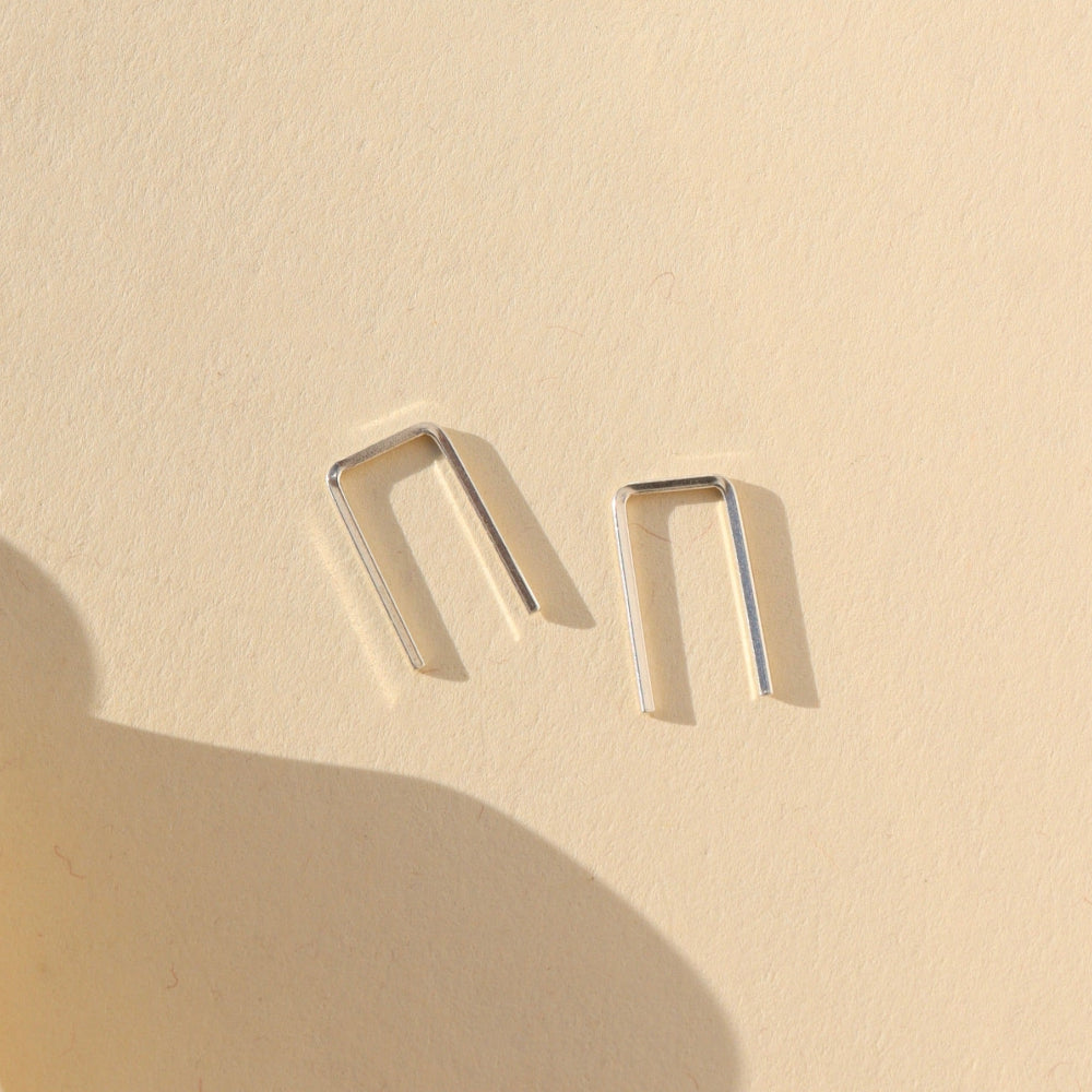 sterling silver mini staples shaped earrings on a light background