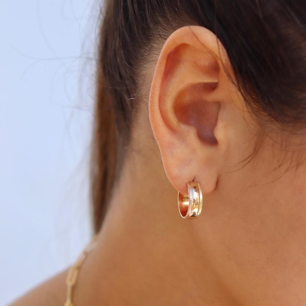 Brunette model wearing the laine hoops. Hoops feature a hammered gold wire with a textured edge. 