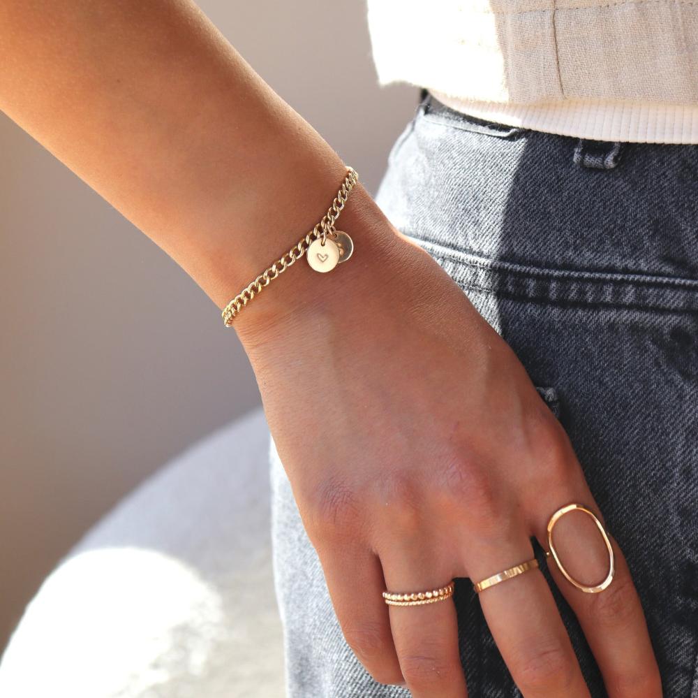 14k gold fill bold link chain Demi Alexandra Bracelet featuring two gold fill disks with a heart and an "S", worn by a model wearing black jeans and a white top