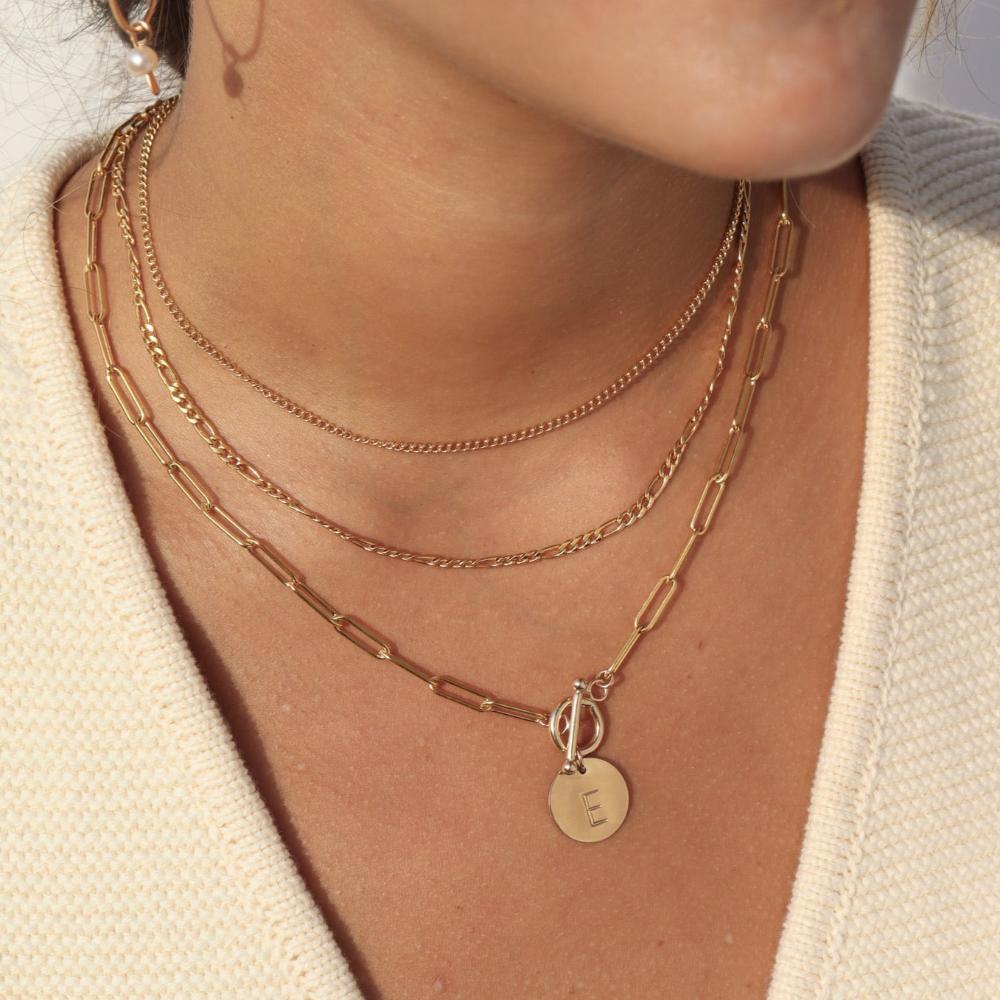 14k gold fill chain link necklace with a toggle clasp and monogrammed "E" flat disk charm, photographed on a model with brown hair, wearing gold jewelry, and pearl hoop earrings