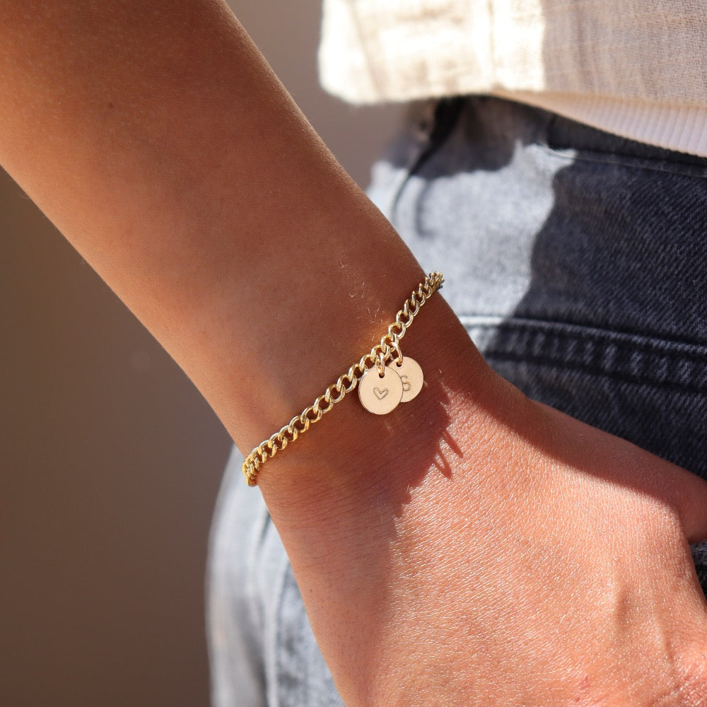 14k gold fill bold link chain Demi Alexandra Bracelet featuring two gold fill disks with a heart and an &quot;S&quot;, worn by a model wearing black jeans and a white top