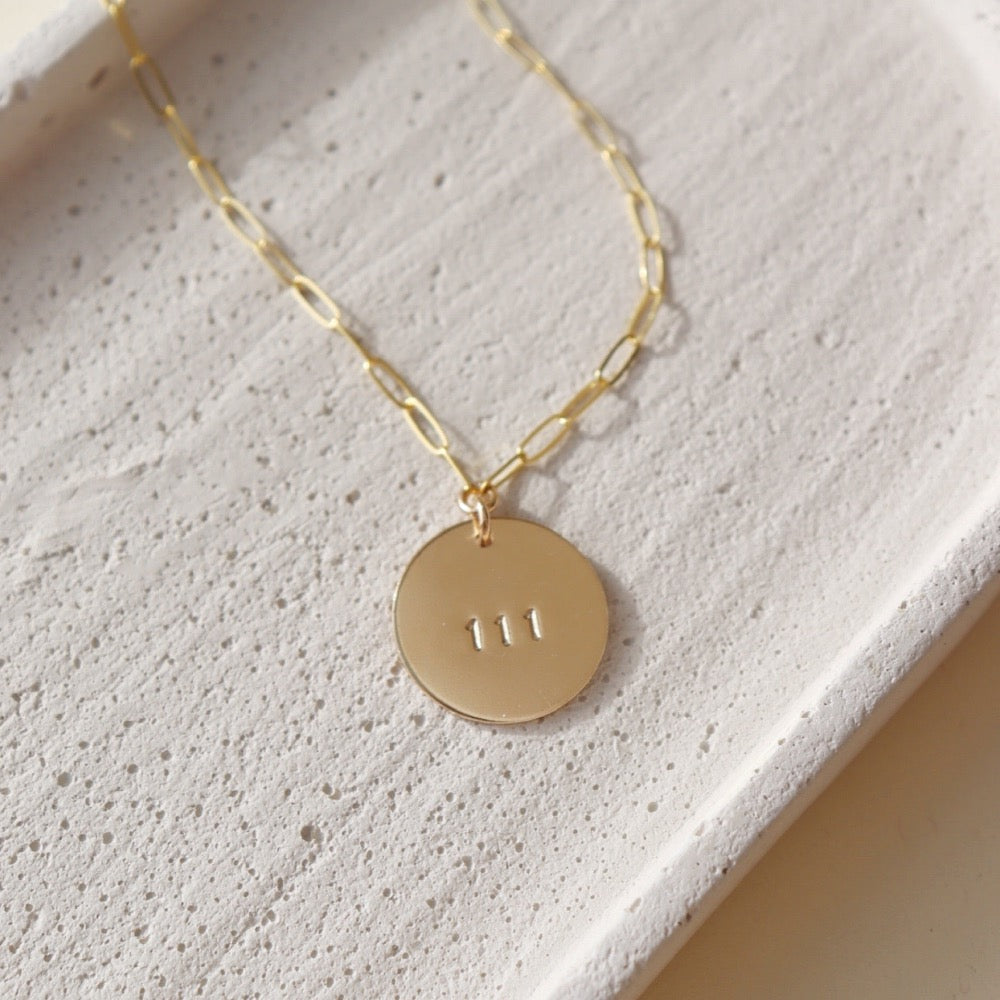 14k gold fill angel number pendant on a gold fill chain, photographed on a ceramic dish