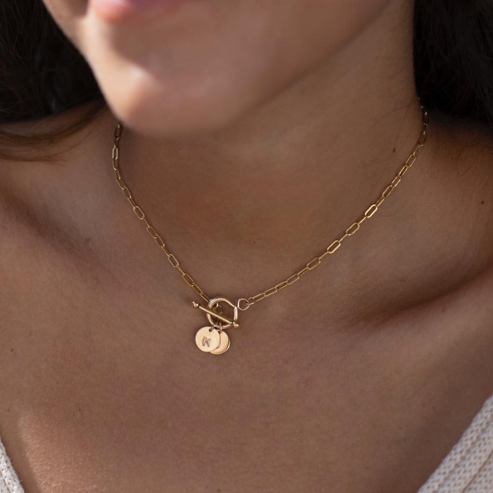 model wearing 14k gold fill monogram toggle necklace. This necklace features the narrow link chain connected by a toggle with the monogram disc.