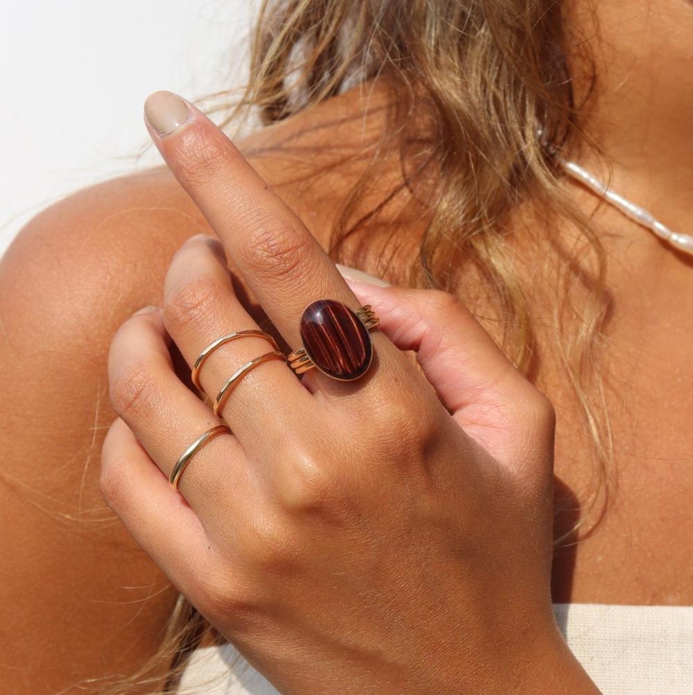 The Scarlett Ring, available in 14k gold fill or sterling silver, features a stunning Red Tiger Eye gemstone on a triple 14k gold fill band