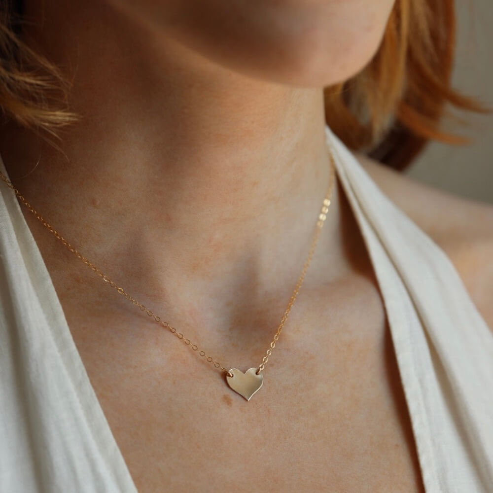 Model wearing 14k gold heart necklace on a 14k gold fill chain, photographed on a model