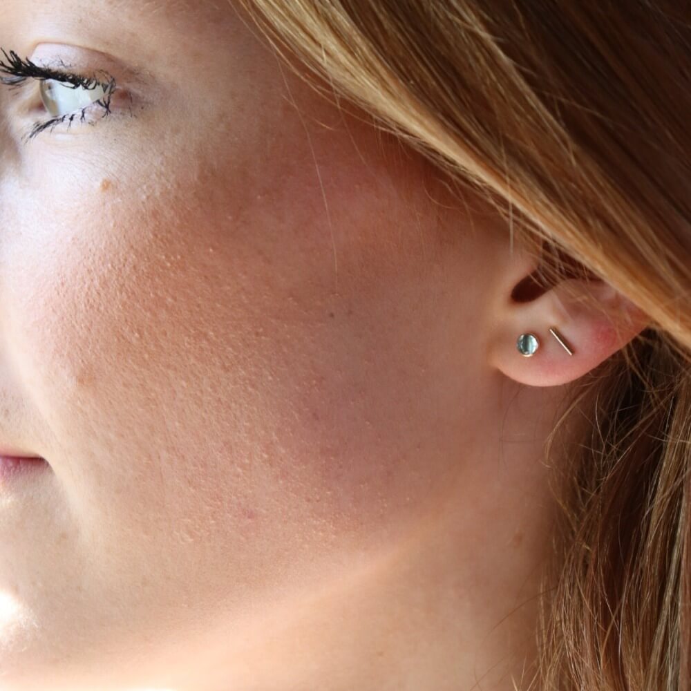 4mm Blue Topaz gemstones set in a 14k gold fill bezel stud earring and placed on a white plate for display. Sold as a pair and perfect for single or double pierced ears. Handmade by Token Jewelry in Eau Claire, WI. Blue Topaz is the birthstone for December.