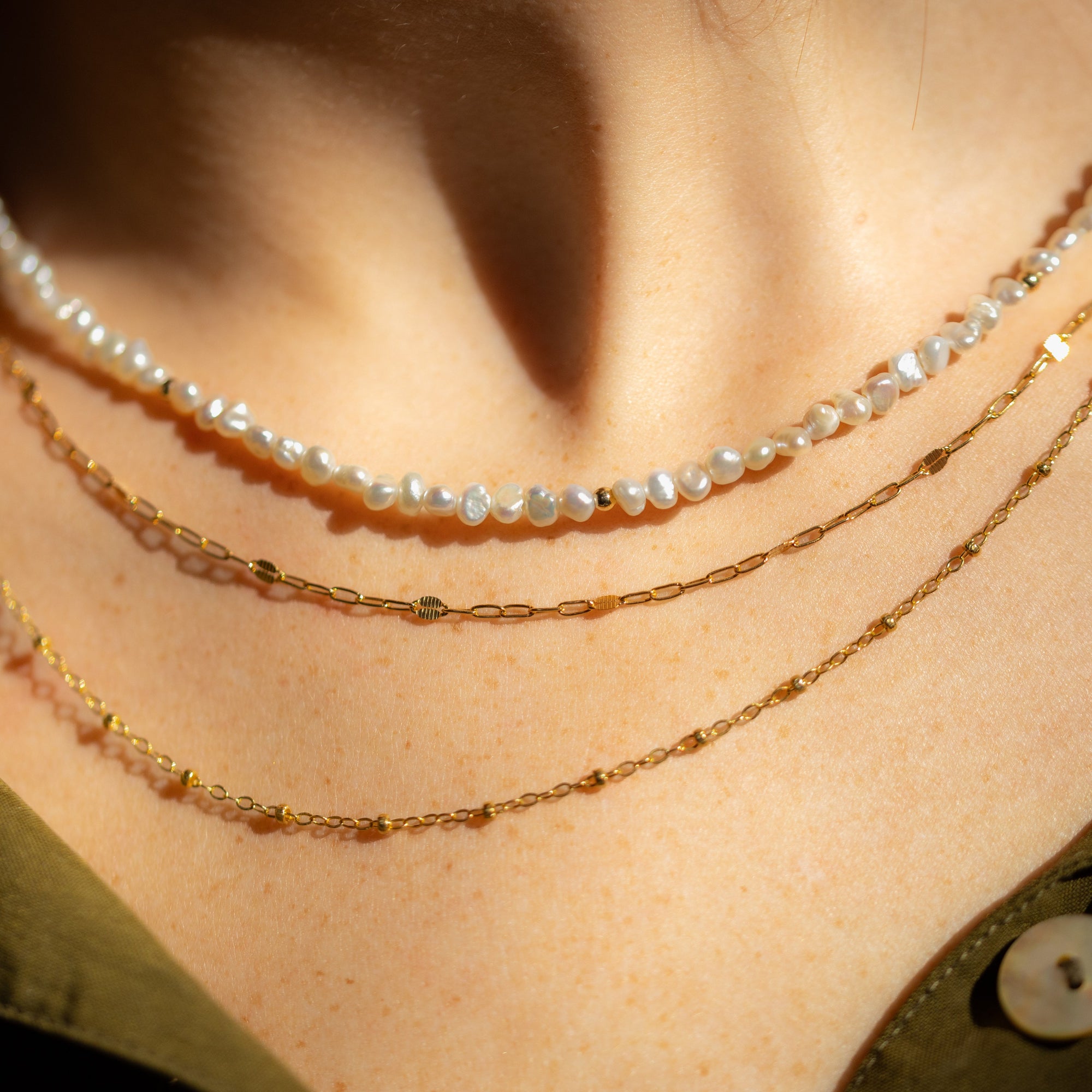 model wearing beaded pearl necklace with 14k gold fill accent beads layered with 14k gold fill dainty chains