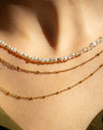 model wearing beaded pearl necklace with 14k gold fill accent beads layered with 14k gold fill dainty chains