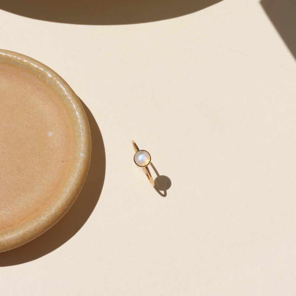 Close-up of stackable moonstone glow ring with iridescent shimmer in gold fill