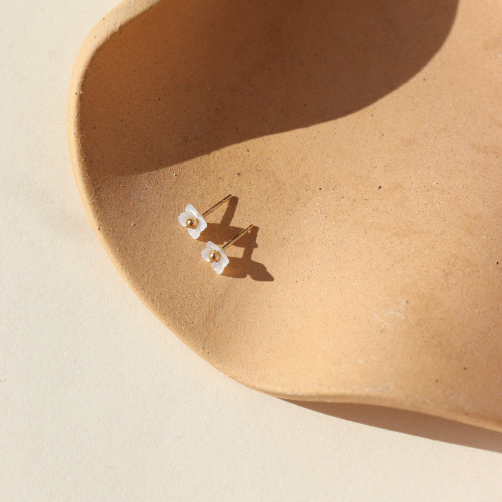 A 14k gold fill classic ball post stud with mother of pearl petals surrounding the stud. 