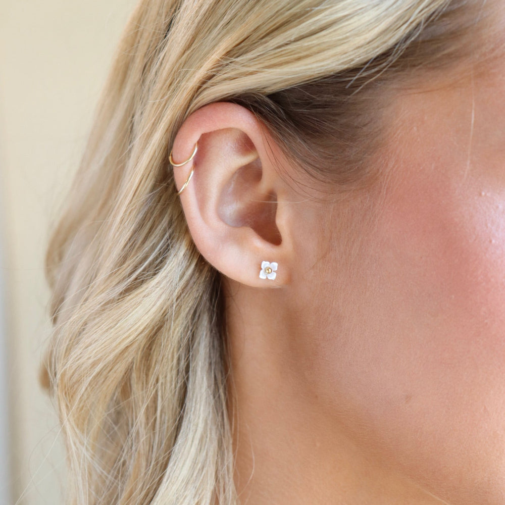 Model wearing a 14k gold fill classic ball post stud with mother of pearl petals surrounding the stud. 