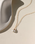 Delicate gold necklace featuring a shimmering oval moonstone pendant with iridescent hues.