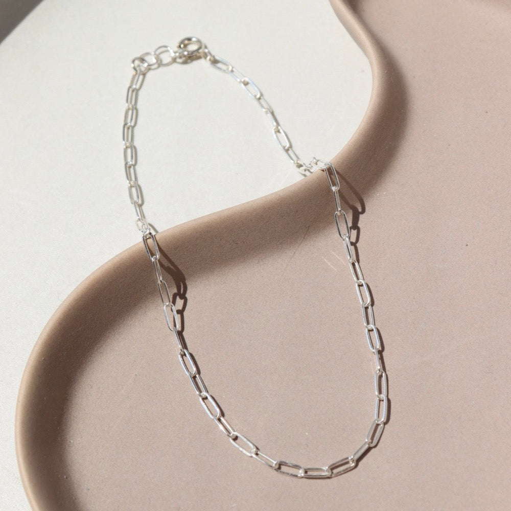 sterling silver delicate paperclip chain anklet on a light dish