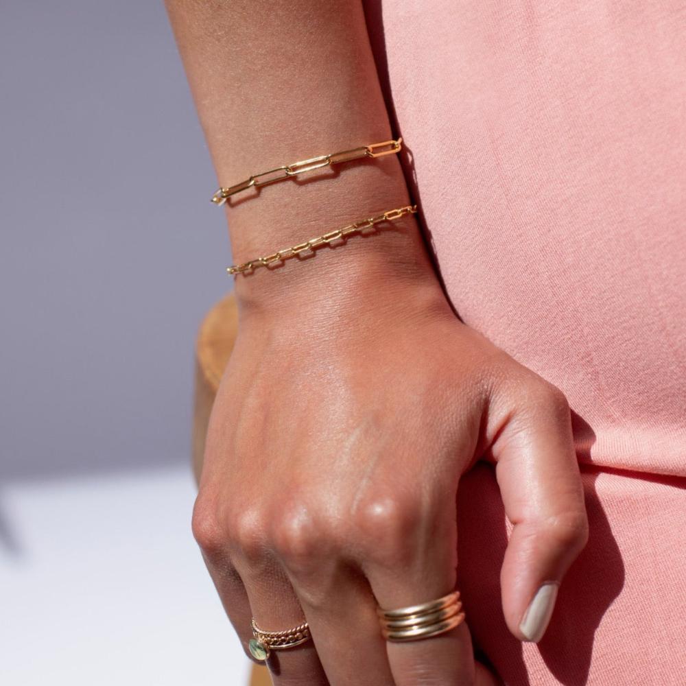 model wearing 2 14k gold fill paperclip chain bracelets 