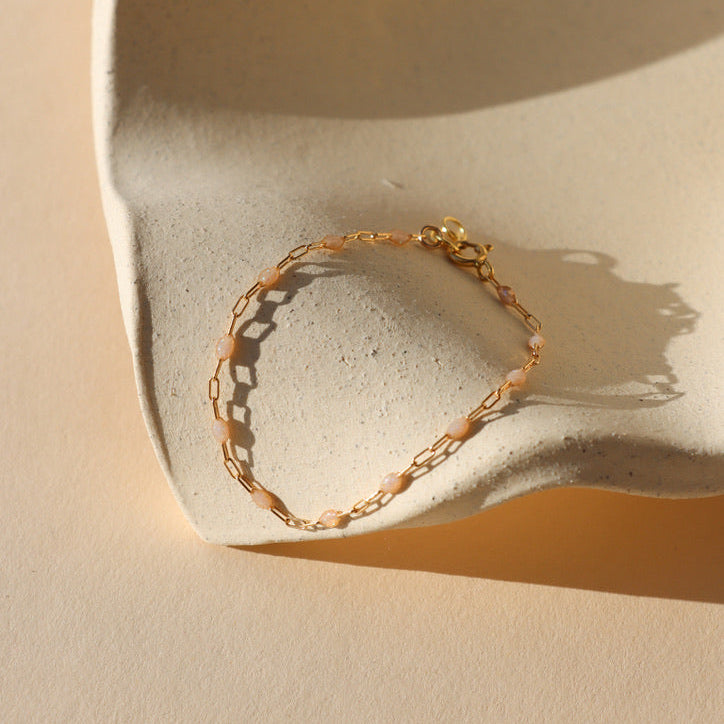 14k gold fill chain alternating with transparent opal gemstones as a bracelet in the sunlight