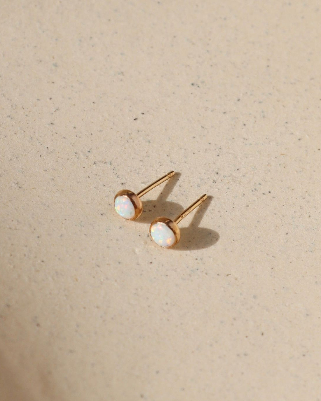 14k gold fill stud earrings with round opal stones in the sunlight