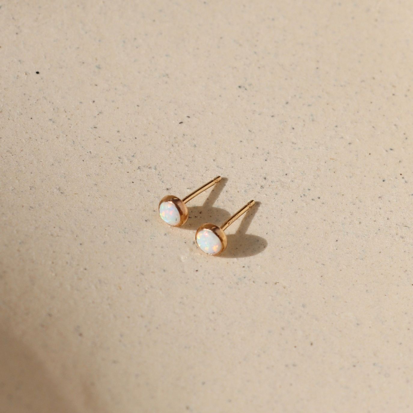 14k gold fill stud earrings with round opal stones in the sunlight