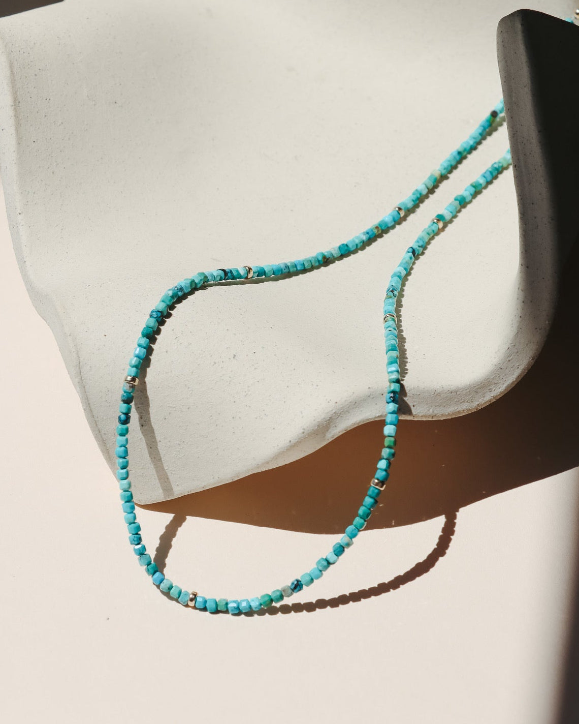 beaded turquoise necklace on a light dish