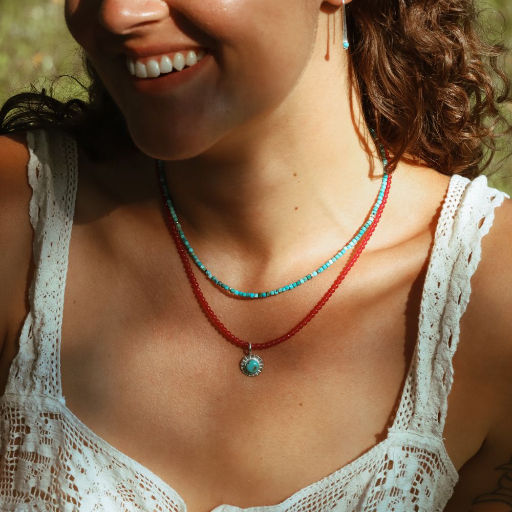 model wearing turquoise and ruby beaded necklaces with round turquoise pendant