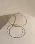 14k gold fill hammered hoop earrings on a light dish