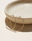 14k gold fill hammered hoop earrings on a light dish