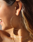 model wearing extra large 14 gold fill hammered hoop earrings in the sunshine