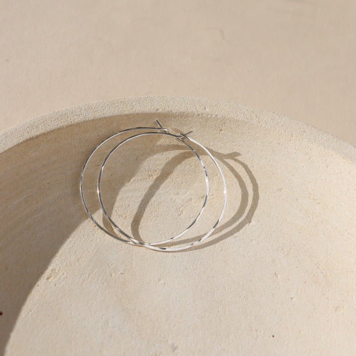 sterling silver hammered hoop earrings on a light dish