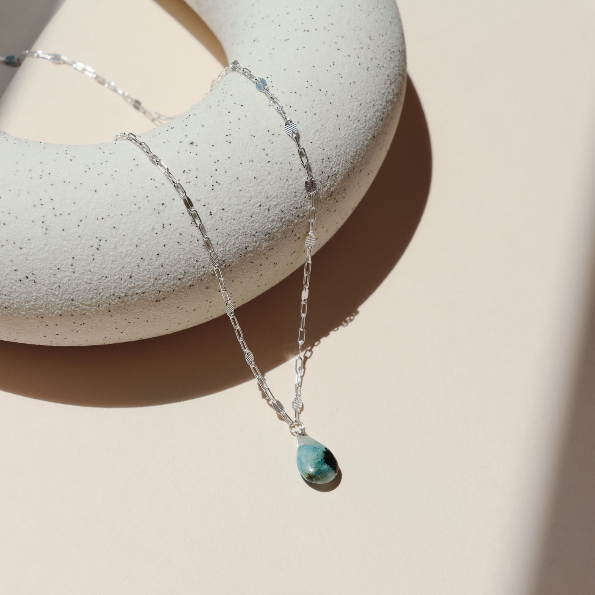 sterling silver chain necklace with teardrop stone pendant in the sunlight