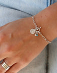 model wearing sterling silver chain bracelet with toggle clasp, birthstone charms, and W disc charm paired with other sterling silver jewelry