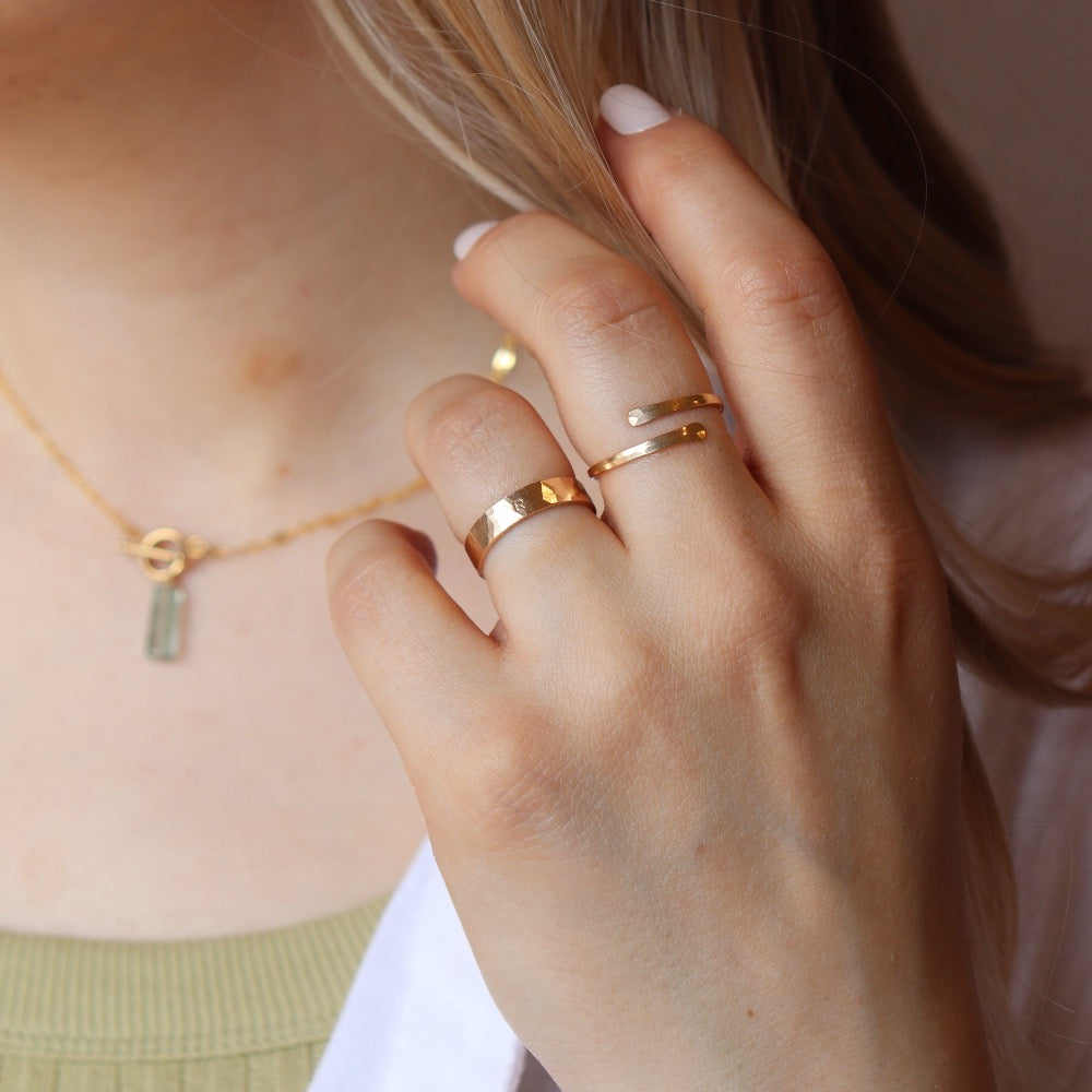 Model wearing 14k gold fill initial stamped ring in the sunlight. This ring features a hammered band that you get to customize with name or initials of your choice.