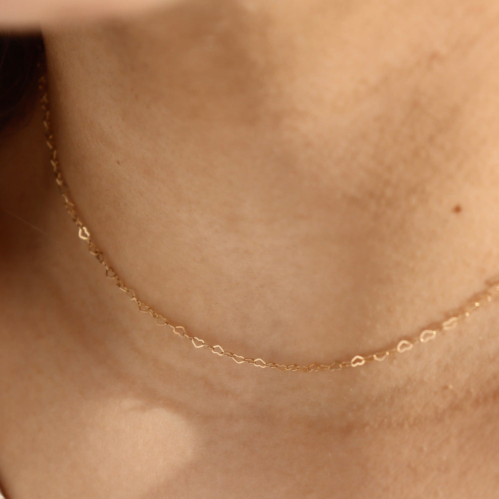 Model wearing the petite heart chain. This chain features a gold tiny heart wire throughout the whole chain. 