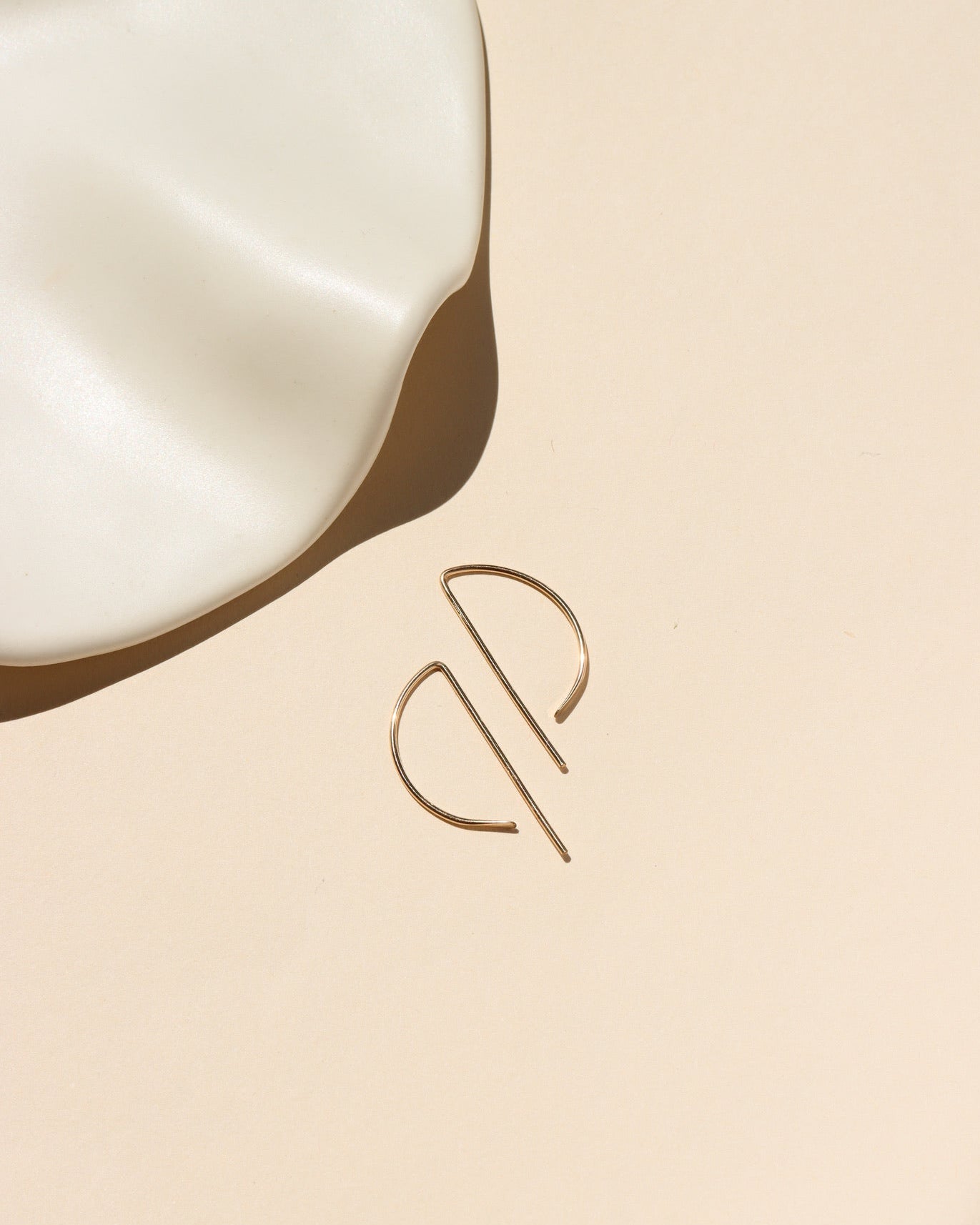 14k gold fill, P shaped threader earrings displayed on a cream backdrop 