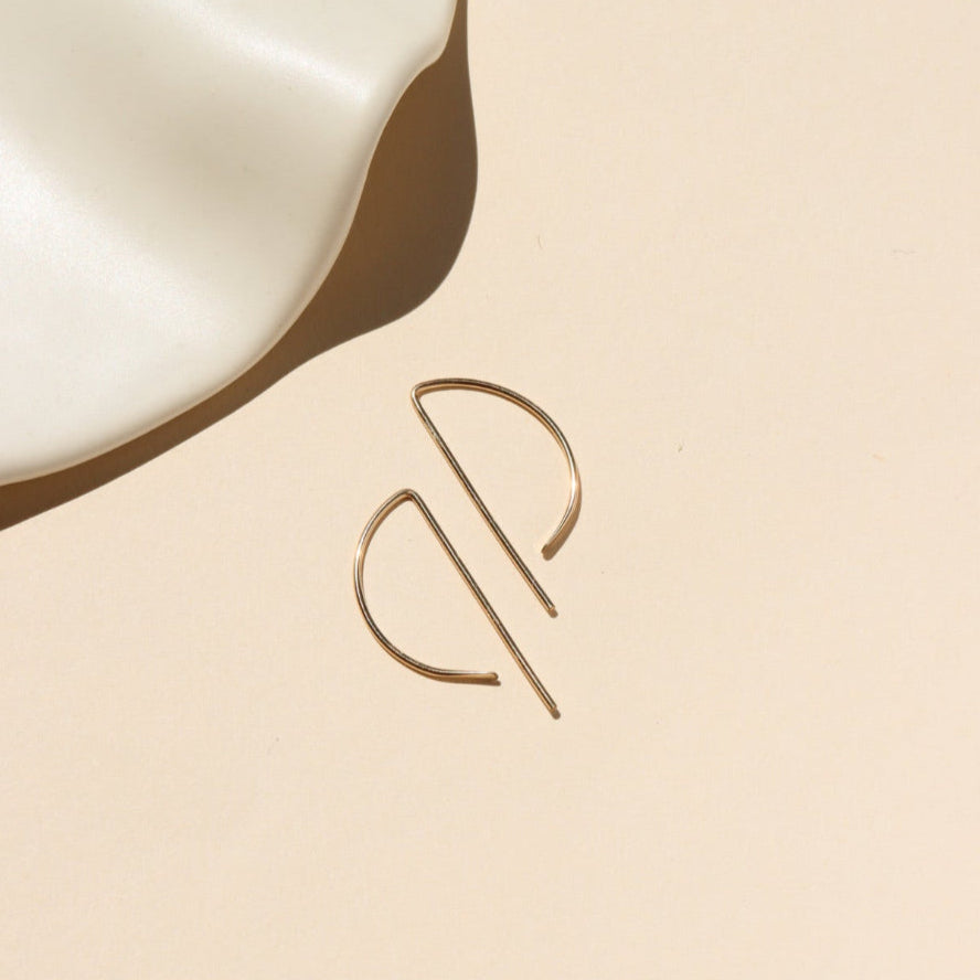 14k gold fill, P shaped threader earrings displayed on a cream backdrop 