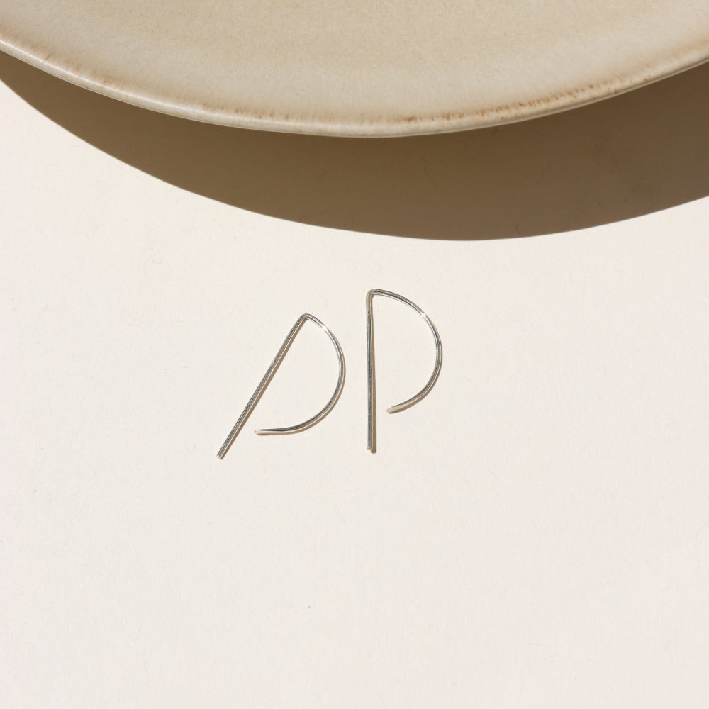 Sterling Silver, P shaped threaders displayed on a cream backdrop 