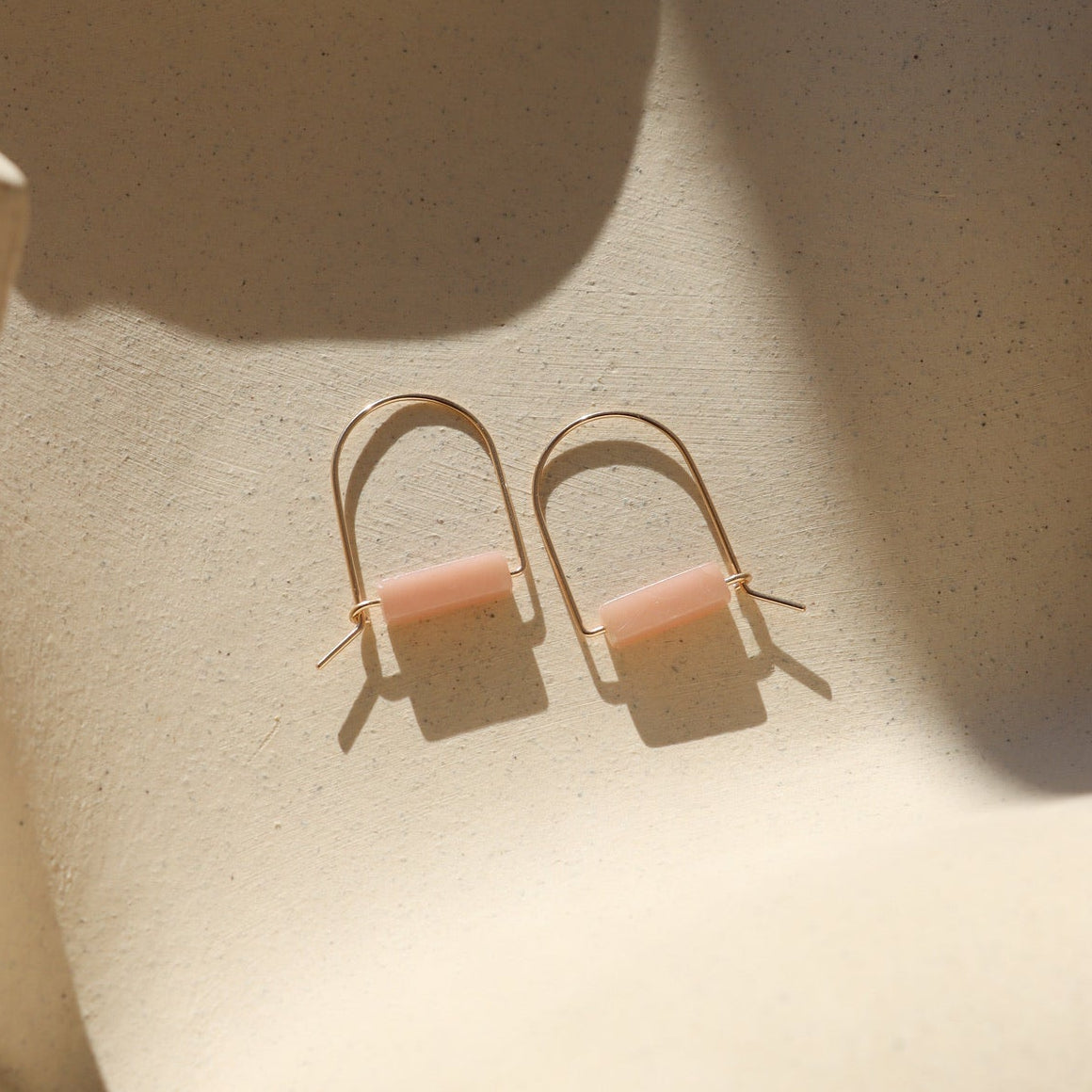 pink opal stones in 14k gold fill arch shaped earrings in the sunlight