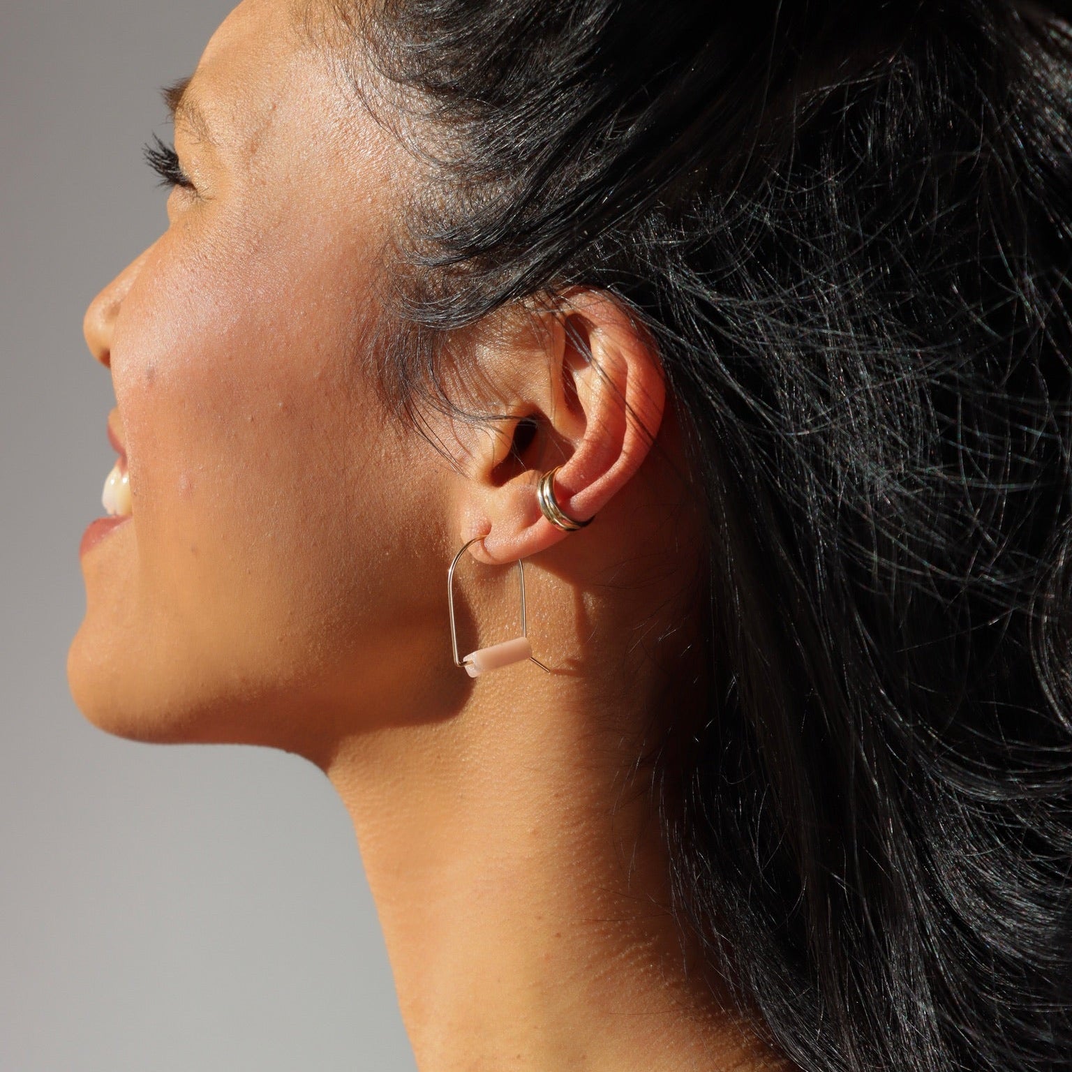 model wearing pink opal stones in sterling silver arch shaped earrings  paired with ear cuff in the sunlight