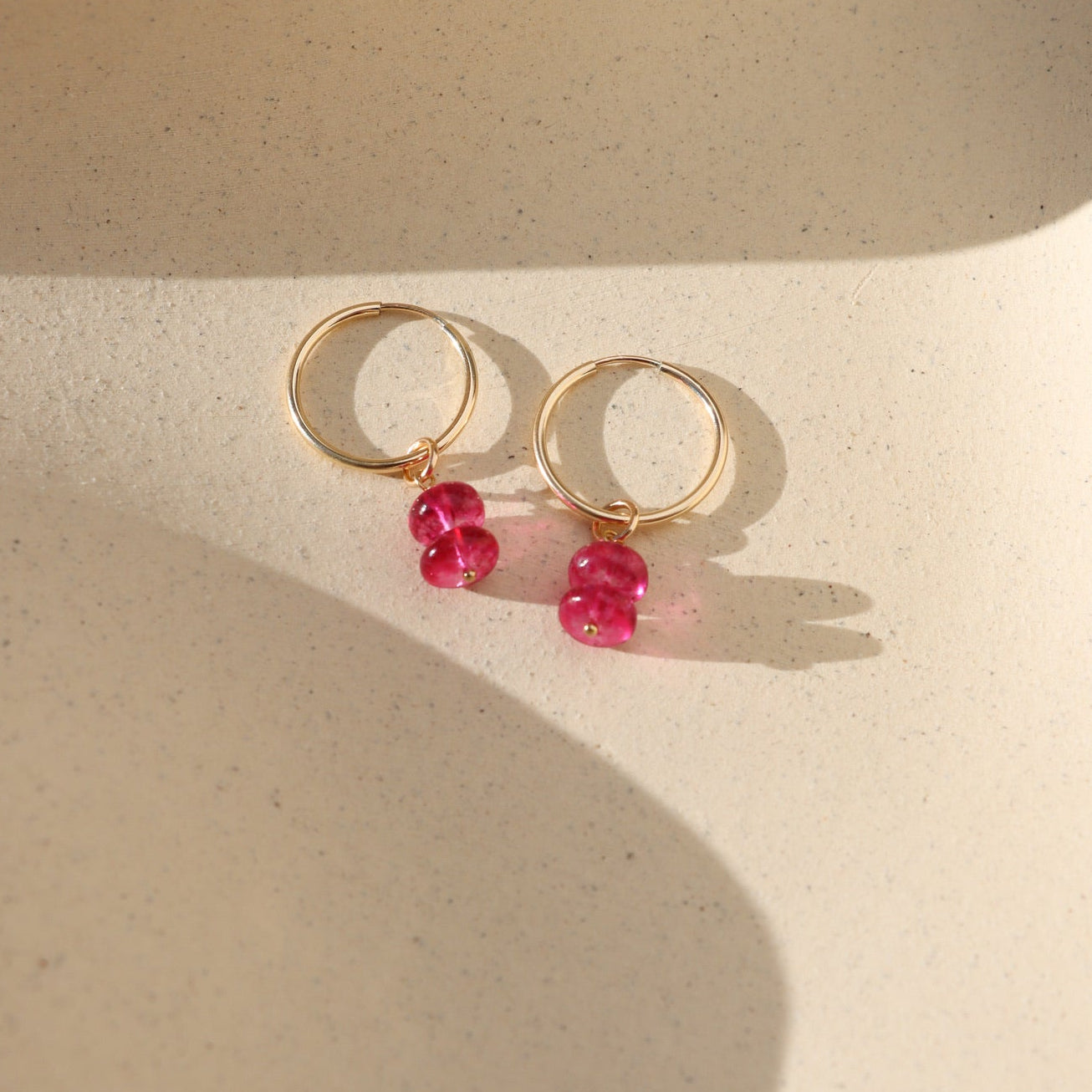 pink topaz charm in 14k gold fill shown on a simple 14k gold fill hoop in the sunlight