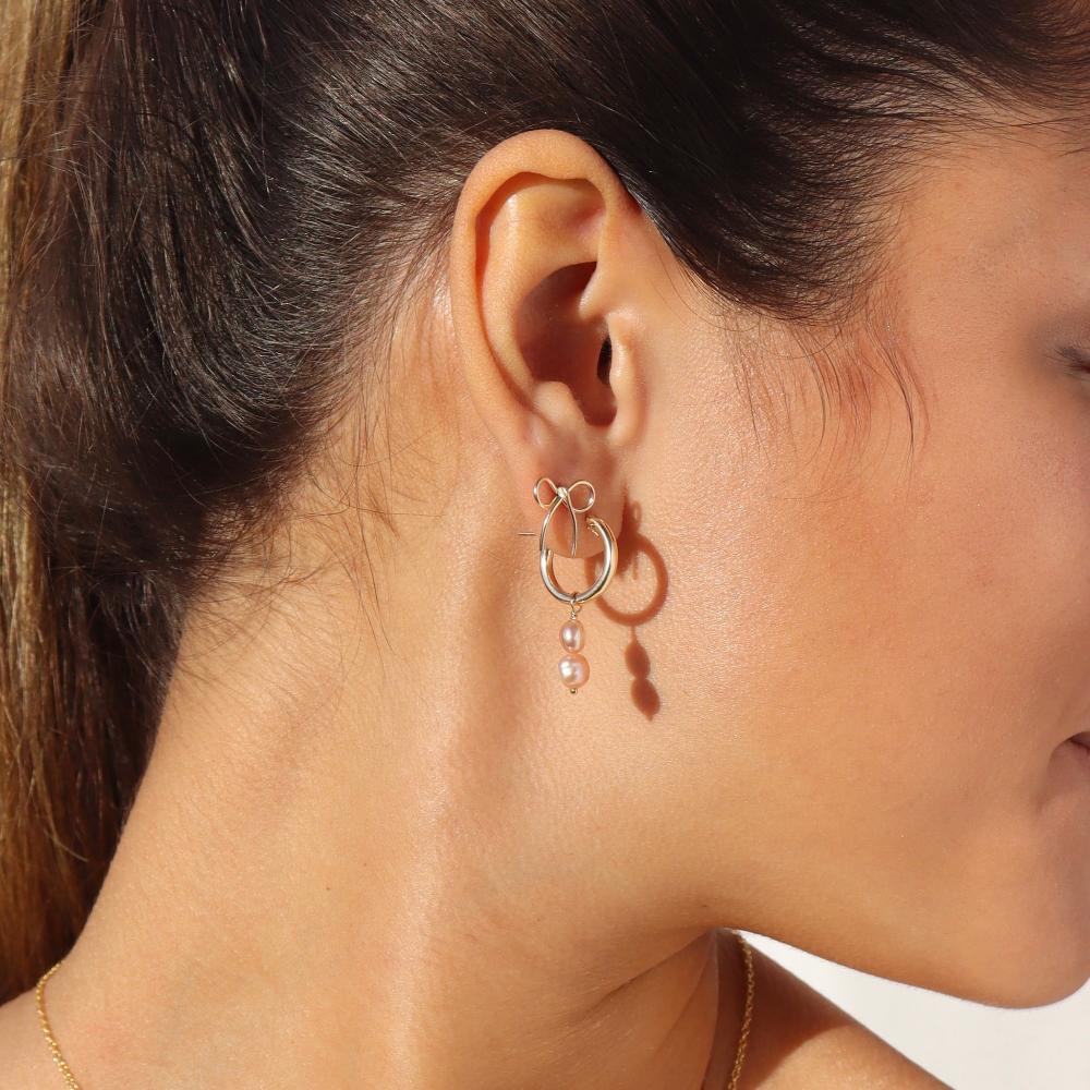 Pink pearl earrings on a brunette model