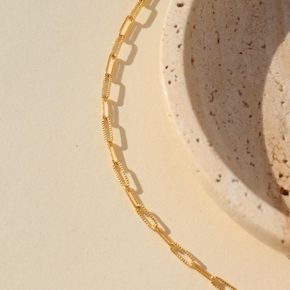 14k gold fill textured paperclip chain anklet on a light surface