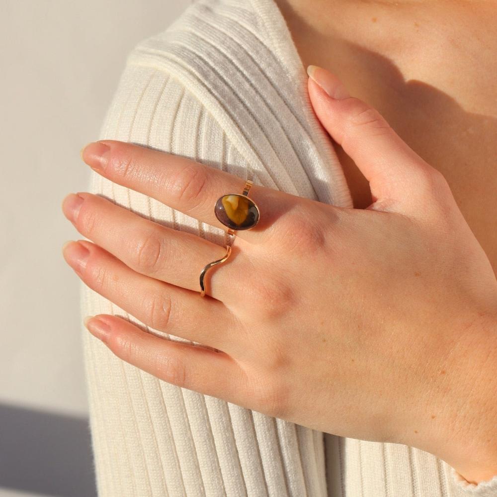 model wearing 14k gold fill hammered ring with plunge detail paired with oval gemstone ring