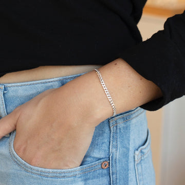 925 sterling silver cuban style chain link bracelet, worn by a model sporting a black sweater and blue jeans
