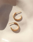 14k gold fill Purity hoops on a peach plate in the sunlight.