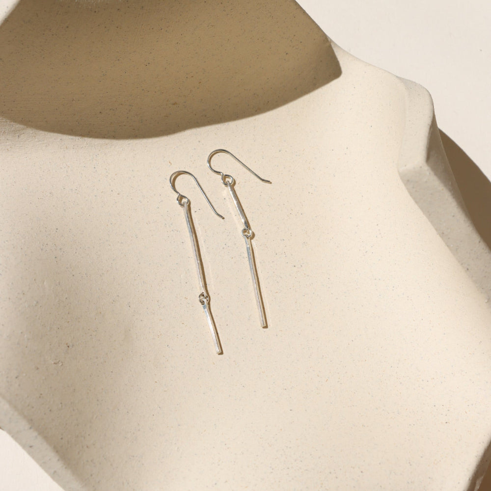 sterling silver dangle earrings on a light dish