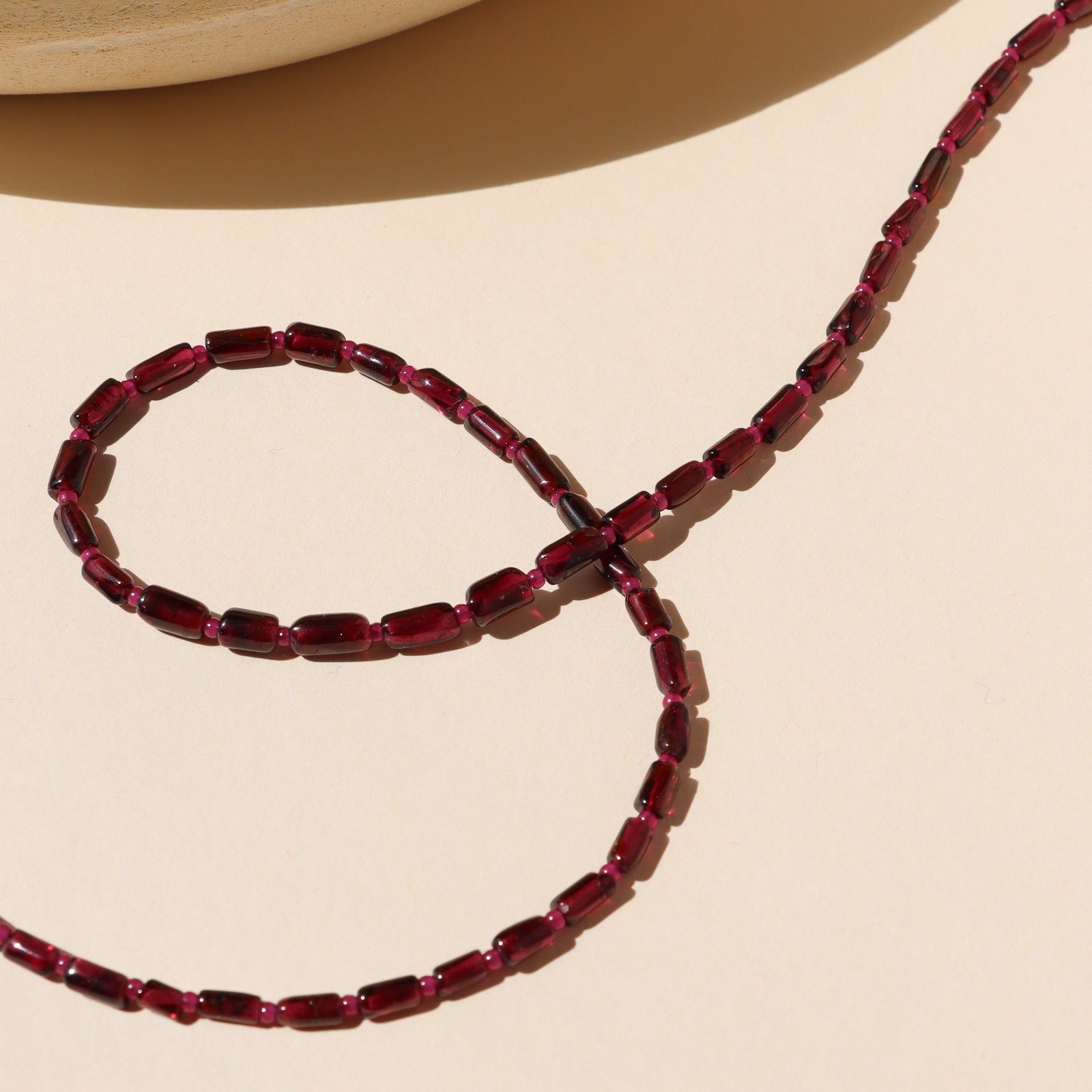 garnet and ruby beaded necklace on a light surface