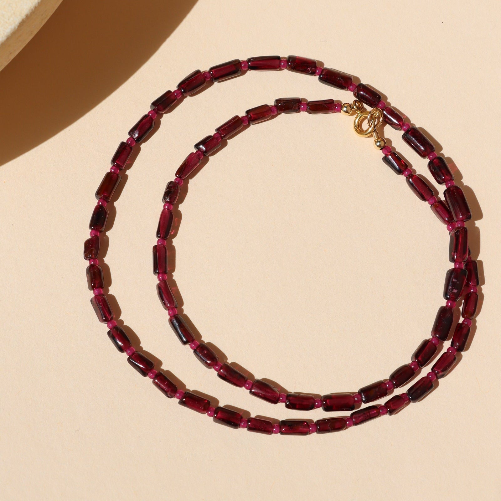 garnet and ruby beaded necklace on a light surface