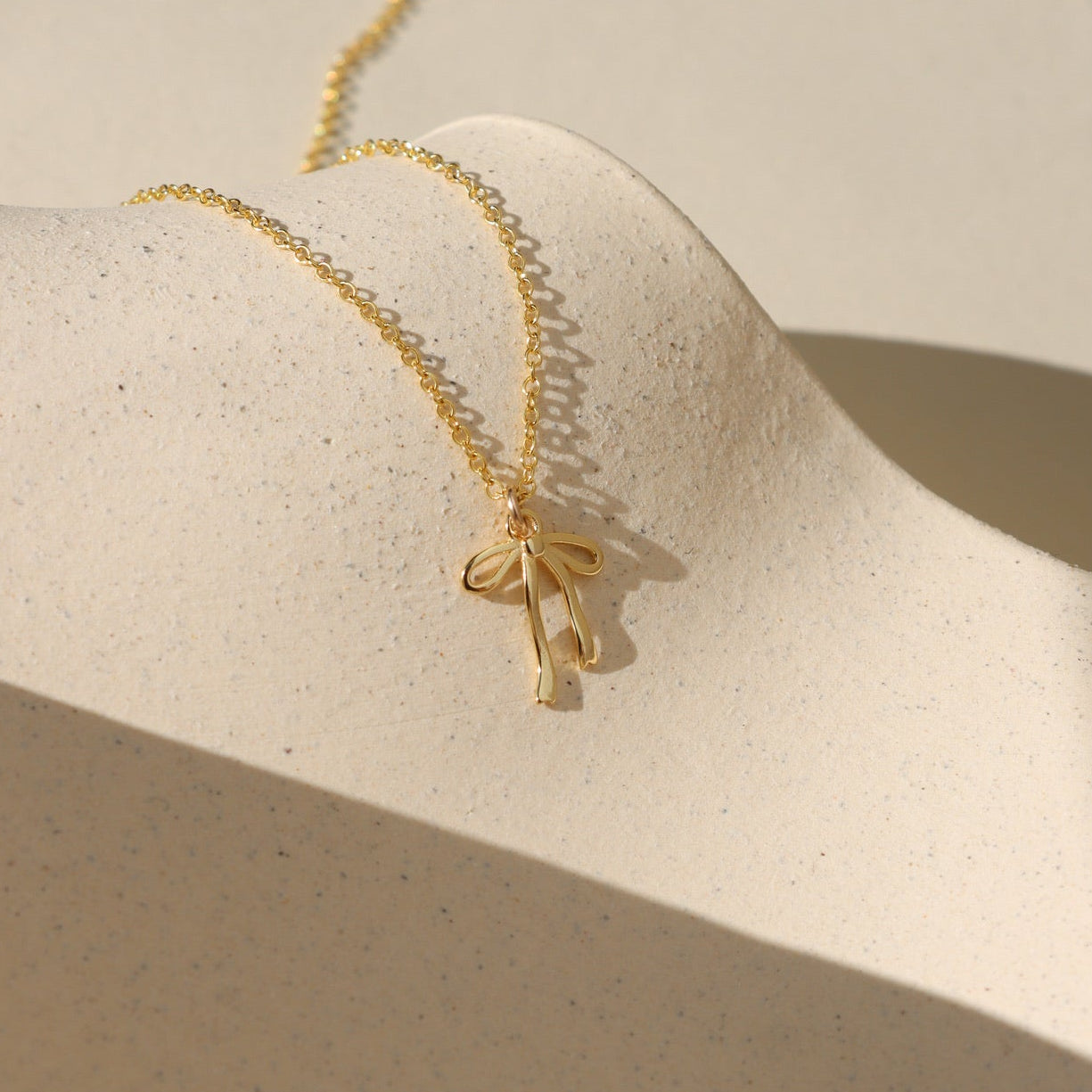 Delicate gold ribbon necklace with a minimalist bow design