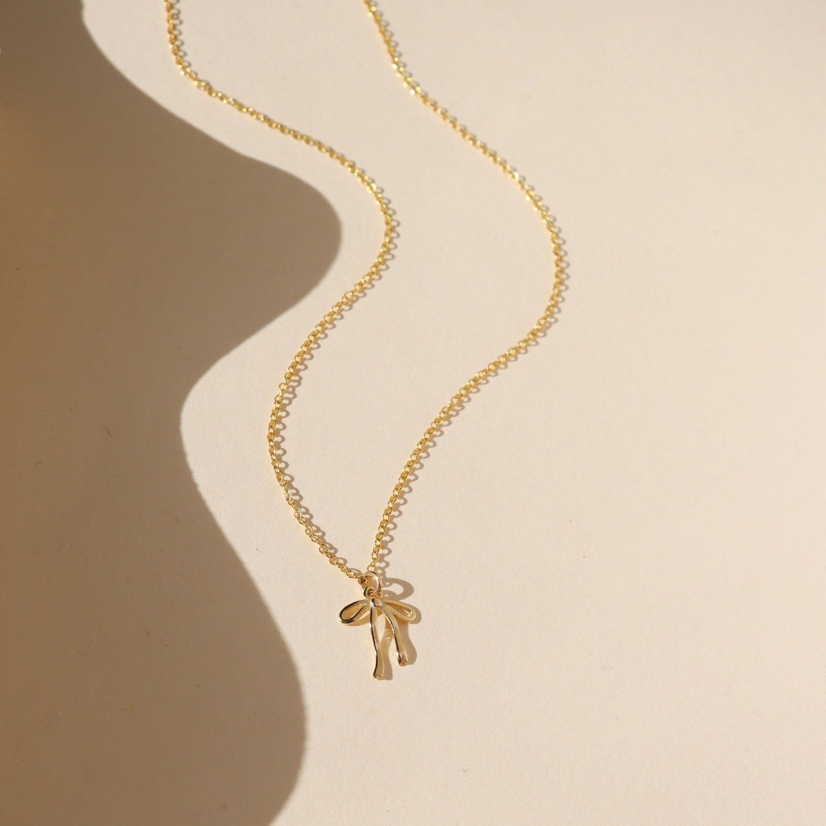 Delicate gold ribbon necklace with a minimalist bow design